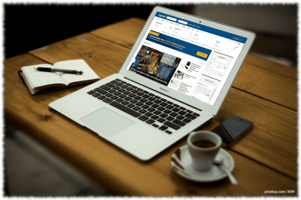 Schreibtisch mit Notebook und Mobilphone. Am Notebook ist die Homepage von barchart.com zu erkennen