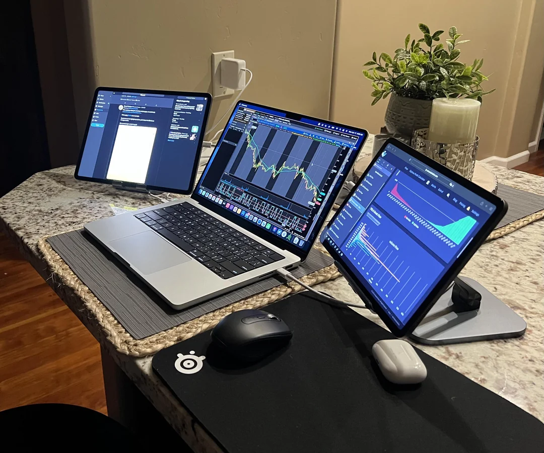 Der beste Trading-Computer: Alles, was Sie für den Einstieg wissen müssen Das Bild zeigt ein Trading Setup mit einem Macbook und zwei Ipads als weitere Bildschirme.