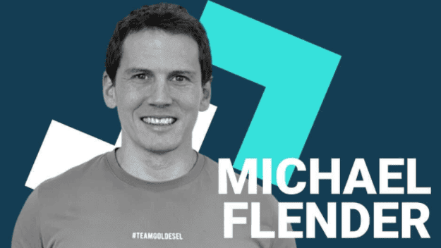 Goldesel.de Erfahrungen (2025) – Alles über die Webseite von Michael Flender Schwarz-Weiß-Foto von Michael Flender, dem Gründer von Goldesel. Er trägt ein T-Shirt mit der Aufschrift "#TEAMGOLDESSEL" und lächelt in die Kamera. Im Hintergrund befindet sich ein dunkelblaues und türkisfarbenes Design mit seinem Namen "MICHAEL FLENDER" in großen, weißen Buchstaben.